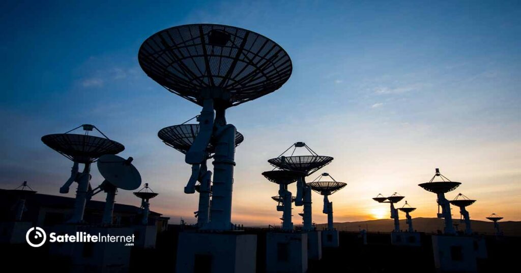 several satellites pointing up to the sunsetting sky