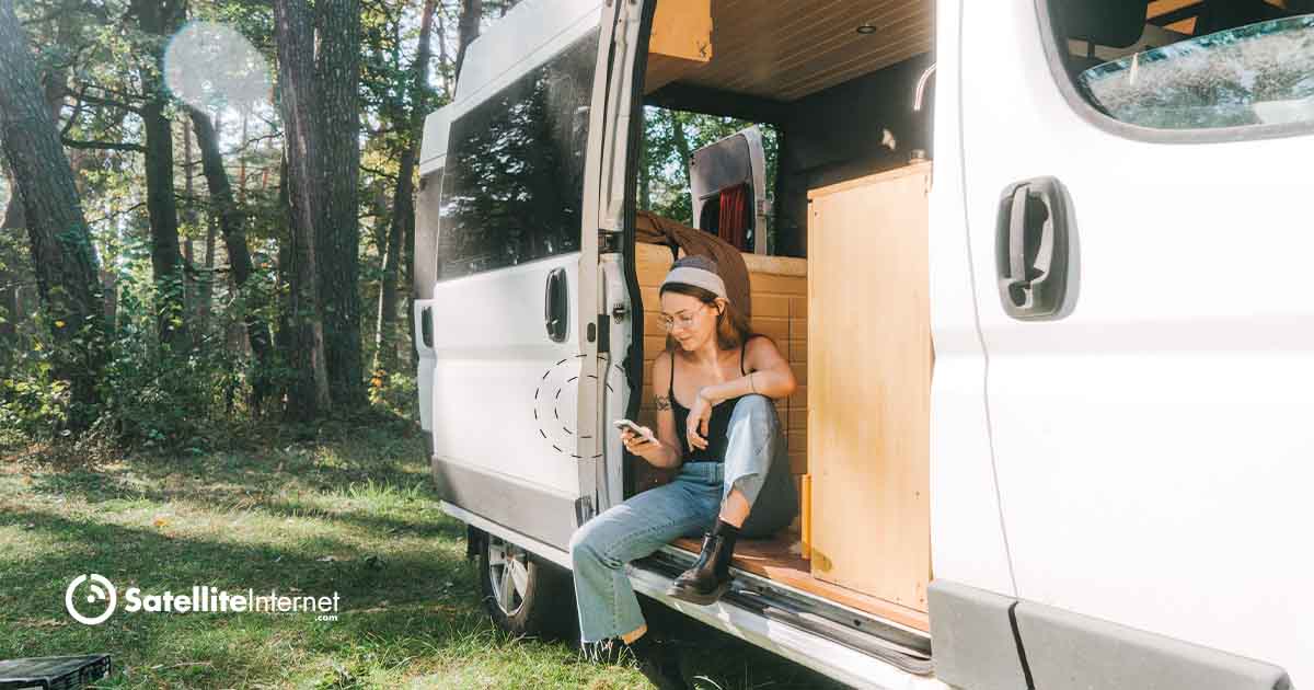 woman sitting in converted camper RV and using mobile device